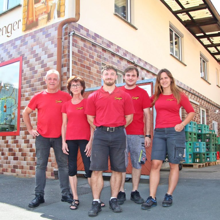 Unsere Süßmostkelterei Fünf Personen in roten Shirts vor dem Eingang zur Süßmosterei Senger.